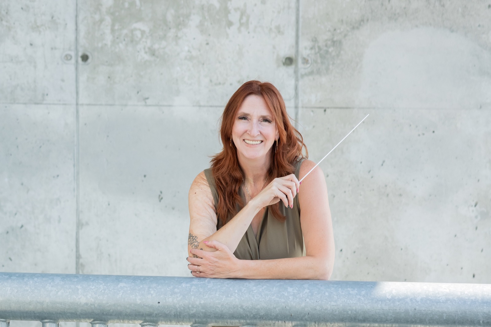 Sarah Batchelor smiling with a conducting baton